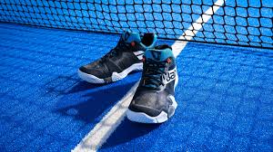 chaussure Babolat pour Padel de couleur noir bleu et blanc sur le court devant le filet