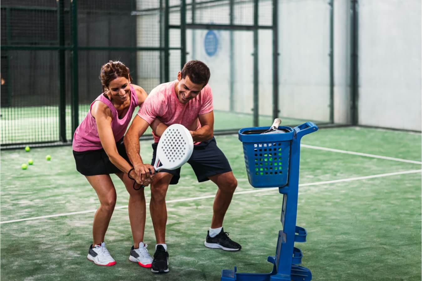 une femme et un homme sur le terrain de Padel et le joueur apprend à la joueuse comment tenir sa raquette de Padel