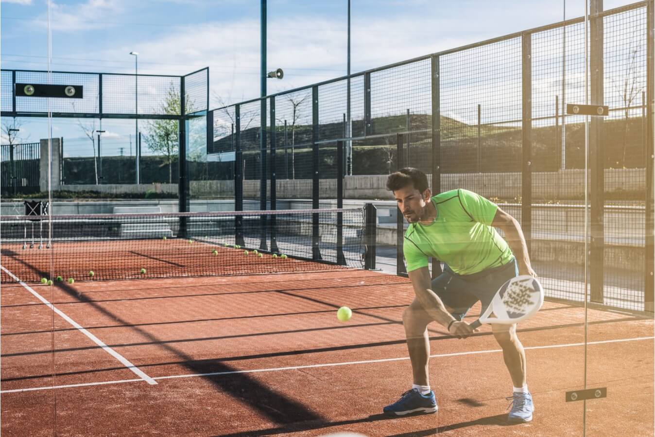 un joueur de Padel sur le terrain entrain de frapper une balle jaune avec sa raquette