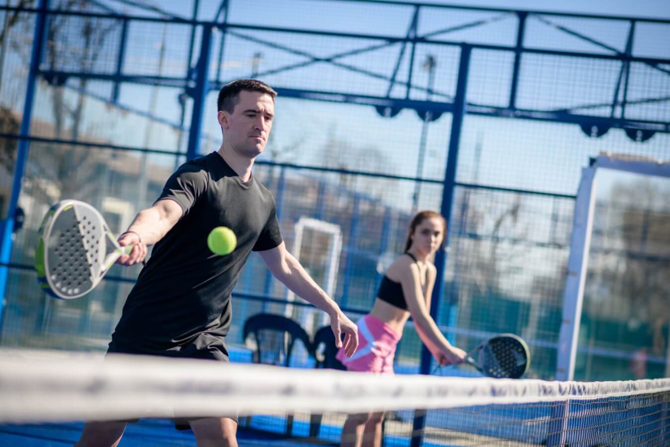 une équipe de 2 joueurs femme et homme avec raquette à la main sur le terrain entrain de jouer