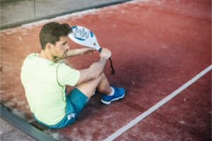 joueur assis sur le terrain avec raquette à la main et une paire de chaussure bleue