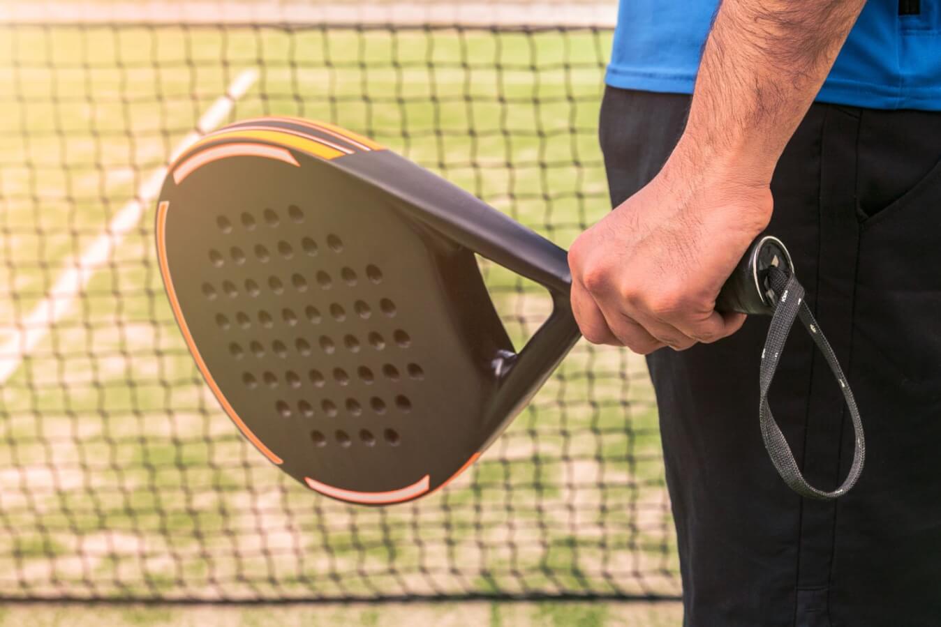 un joueur de Padel près du filet tient une raquette noire