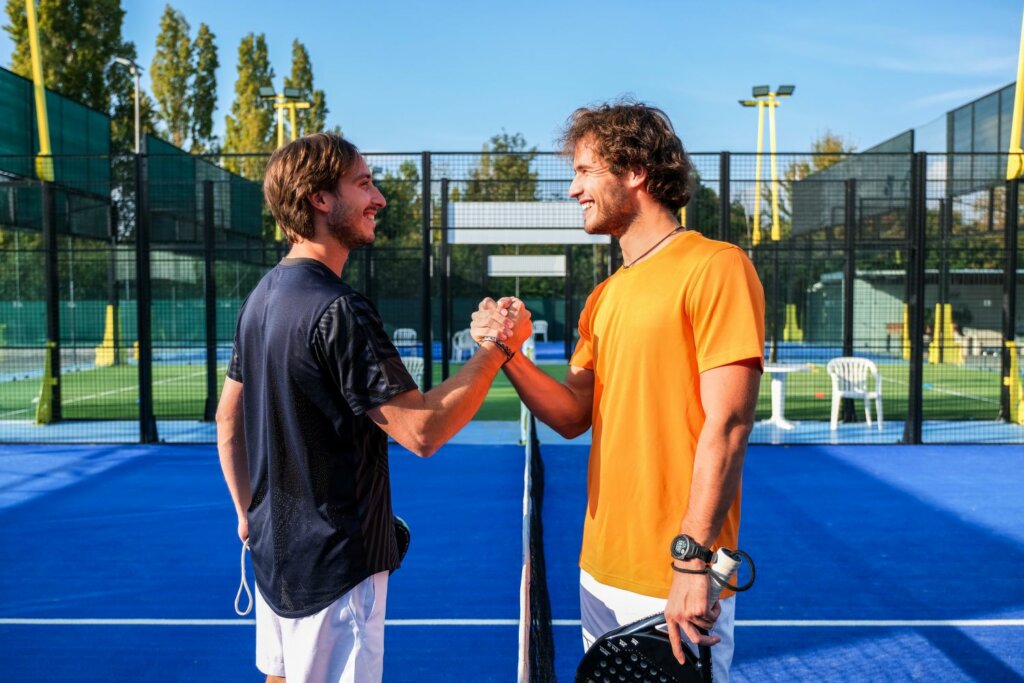 2 joueurs de Padel se tenant amicalement la main près du filet sur un terrain