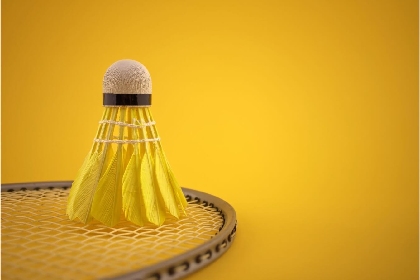 fond jaune avec au premier plan, volant et raquette de badminton