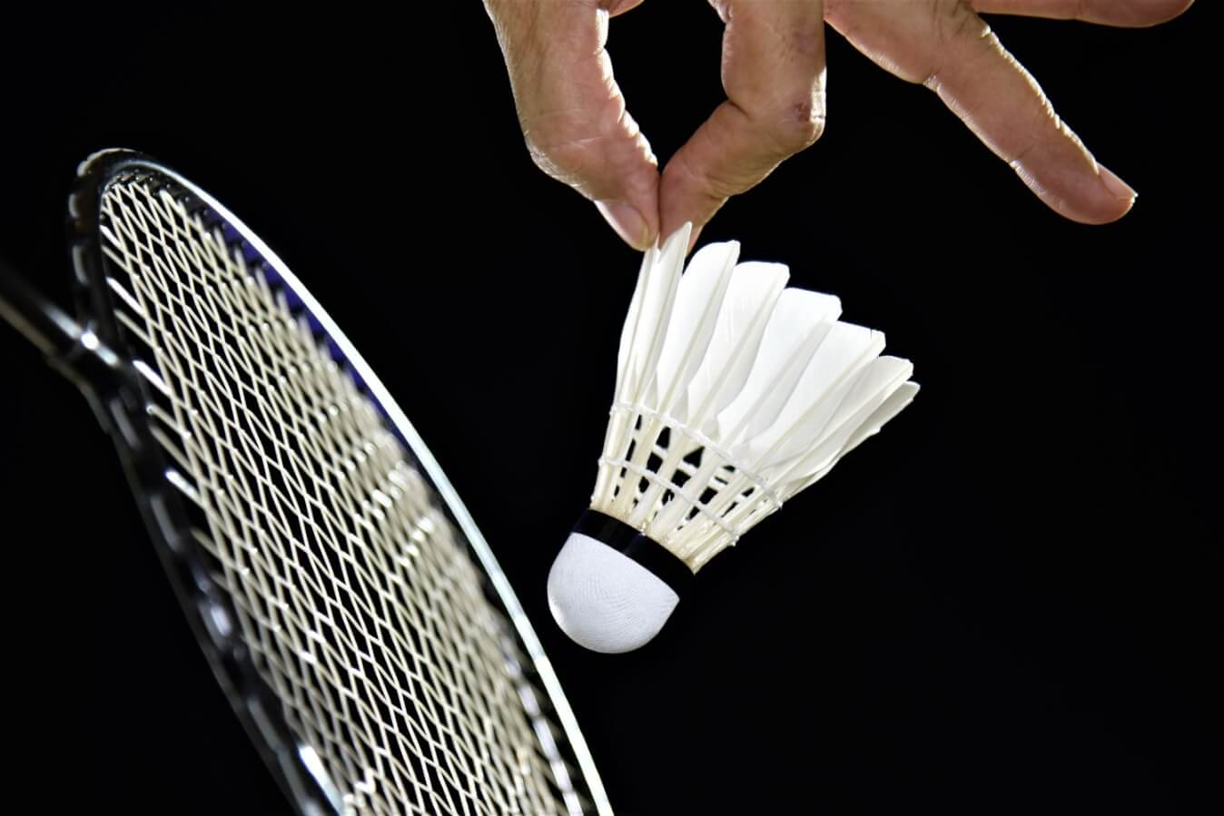 raquette,main et volant de badminton sur un fond noir