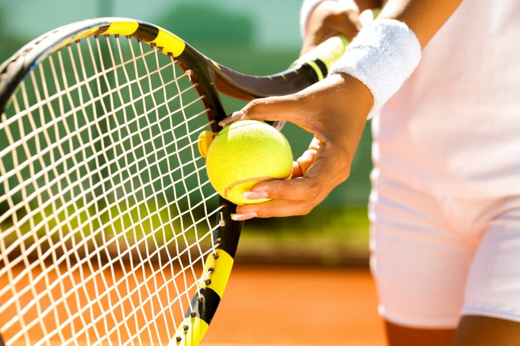 main d'une joueuse de tennis tenant une raquette et une balle