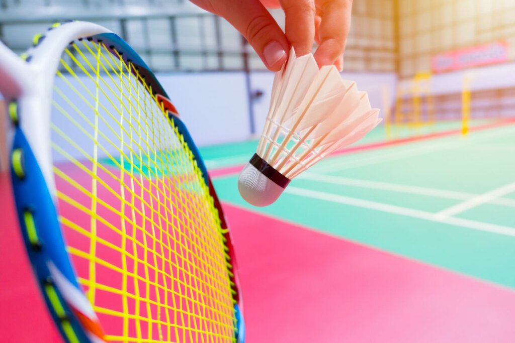raquette et volant tenue par une main sur un terrain de badminton