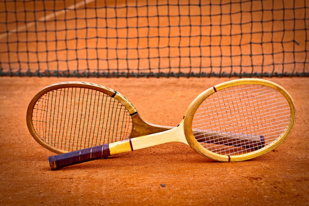 2 raquettes de tennis posées sur le sol en sable près d'un filet